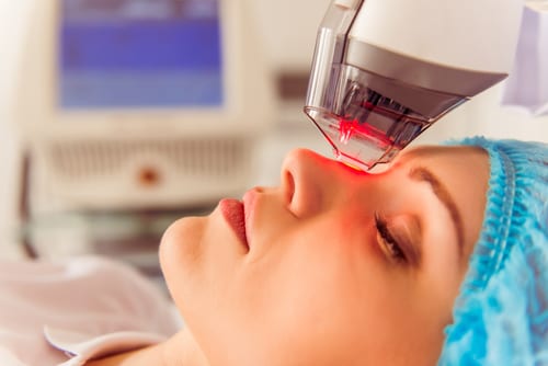 female patient is getting a face skin treatment while lying at cosmeticians office